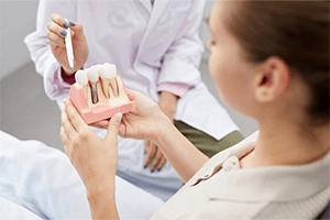 A patient holding a model of a dental implant