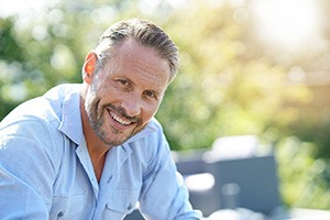 Man sitting down outside on sunny day while smiling