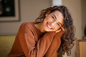 Woman in orange sweater leaning forward and smiling