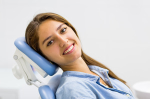 Woman sitting in dental chair and smiling